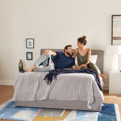 Couple enjoying a clean room with a new firm mattress and made bed to sleep on