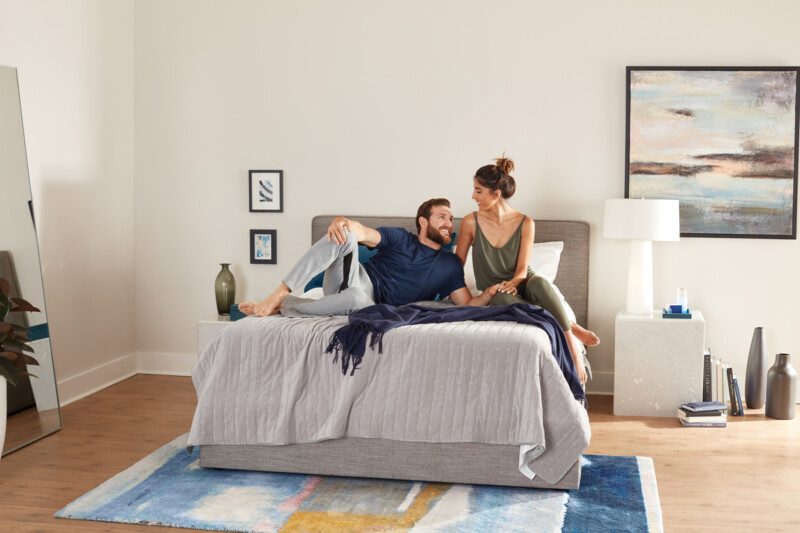 Couple enjoying a clean room with a new firm mattress and made bed to sleep on